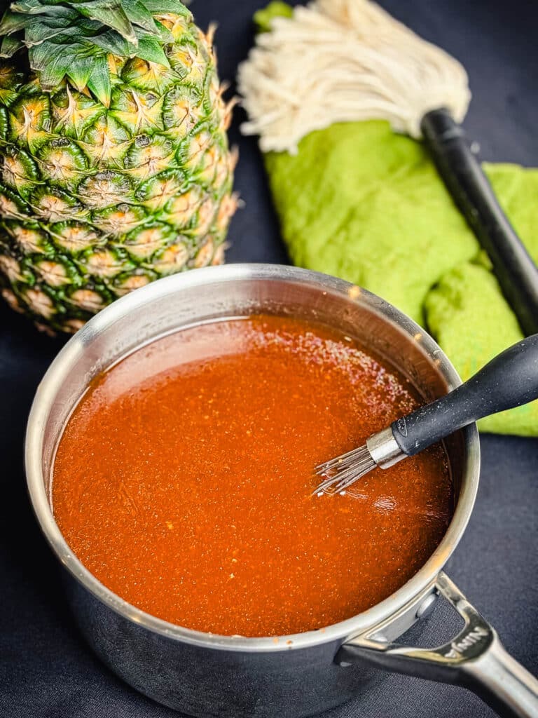huli huli sauce in a saucepan with a pineapple in the background