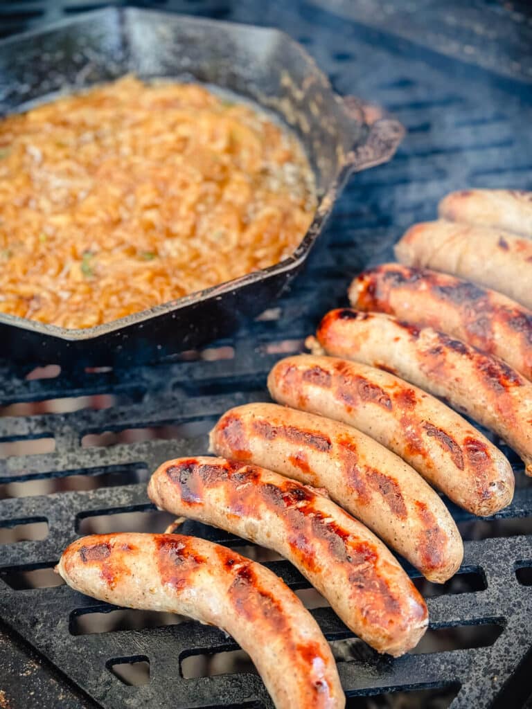 beer brats on a grill grate directly over hot coals