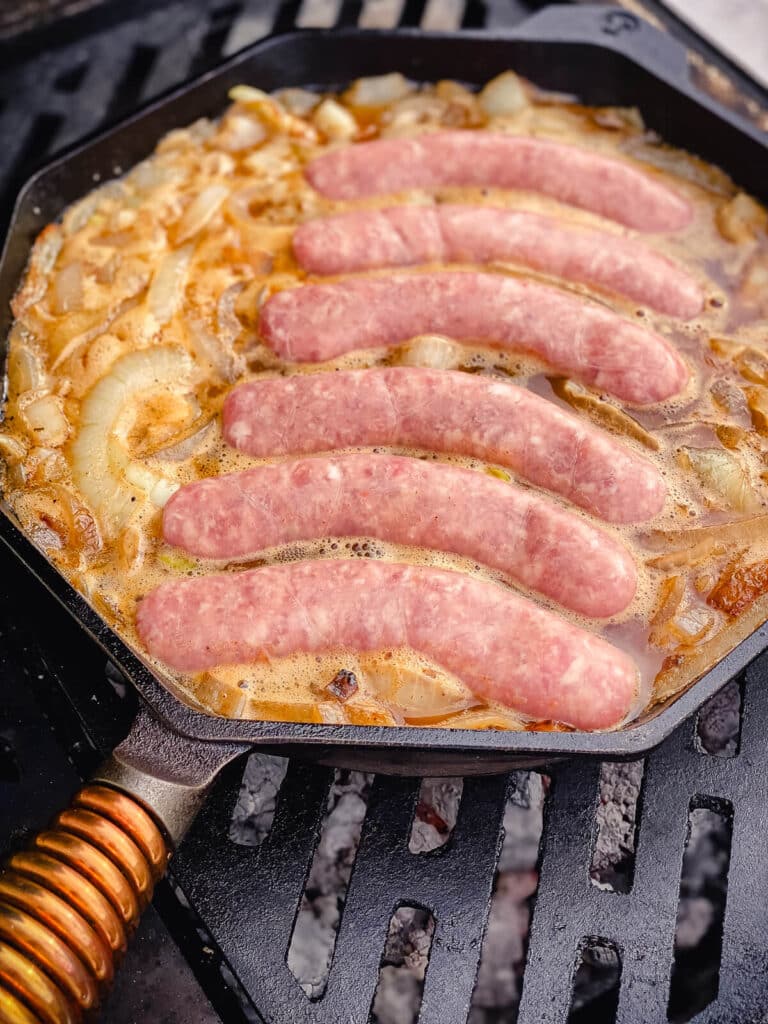 brats in a pan full of beer and onions