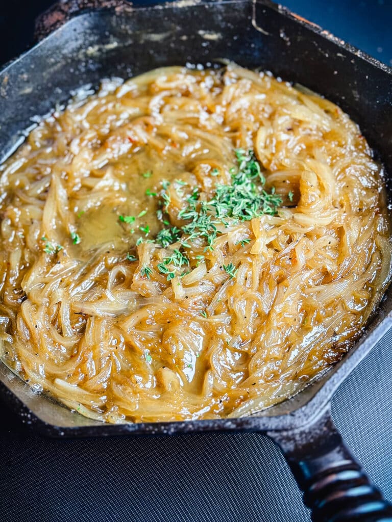 cooked onions in a cast iron pan with fresh thyme