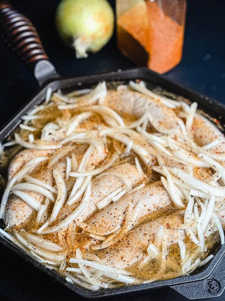 seasoned brats in a skillet of onions and beer