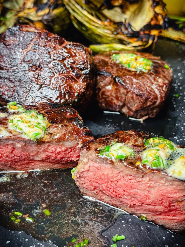 butter melting over a grilled ribeye that has been sliced in half