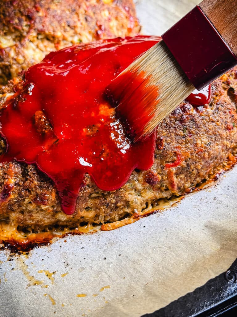 sauce being brushed on turkey meatloaf