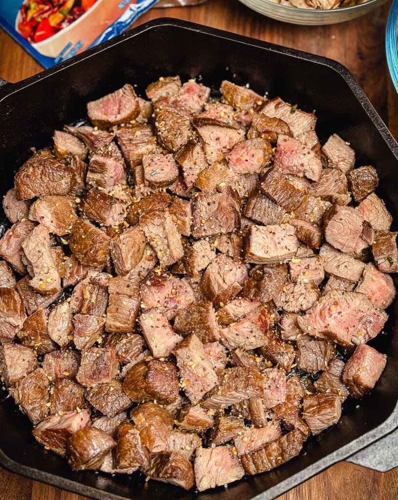 cubes of beef in a cast iron pan