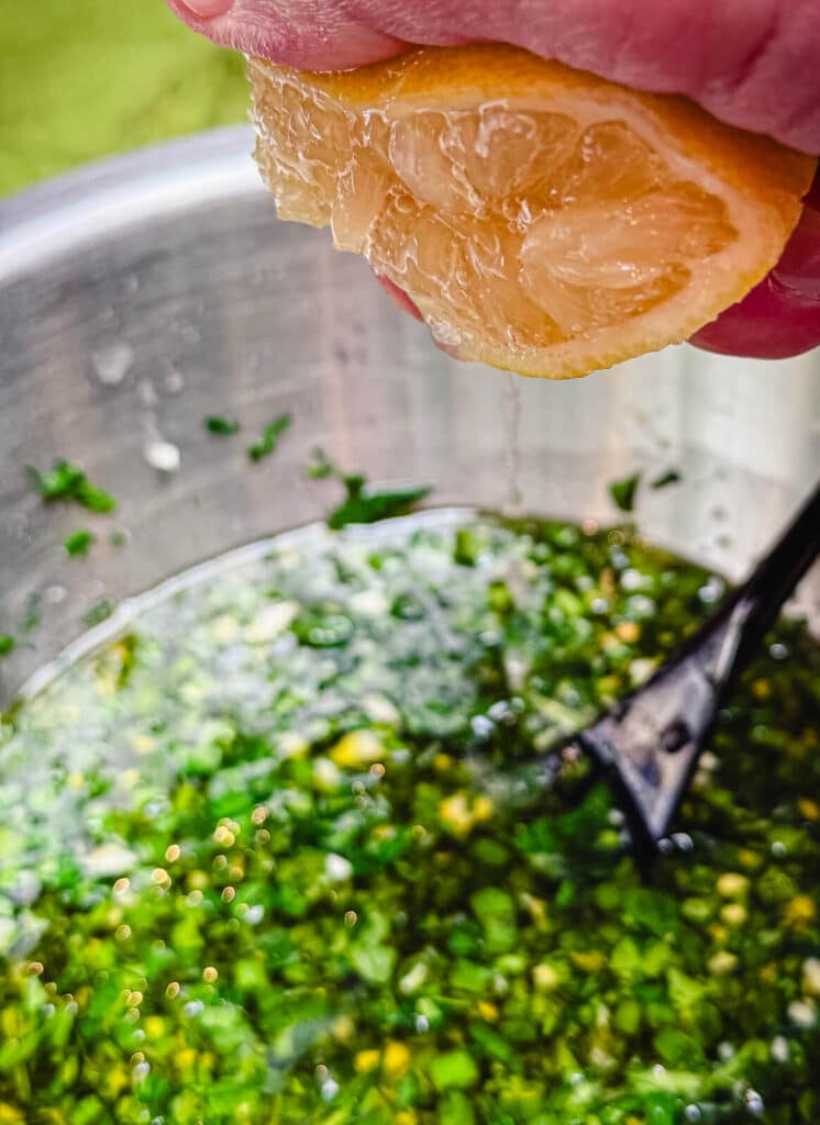 lemon being squeezed into fresh herbs