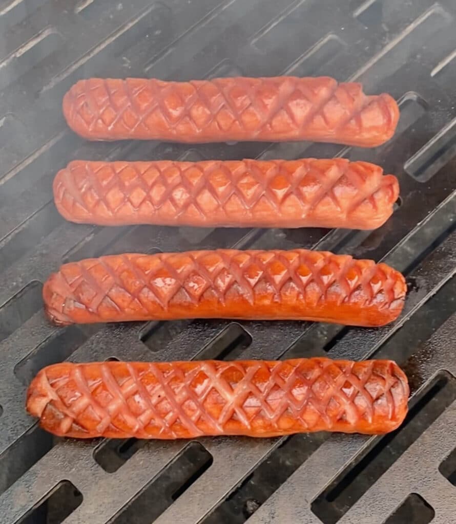 scored hot dogs on a grill