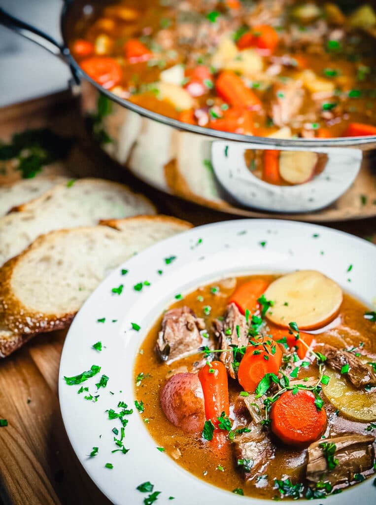 Irish stew in a large bowl with a pan of stew in the background