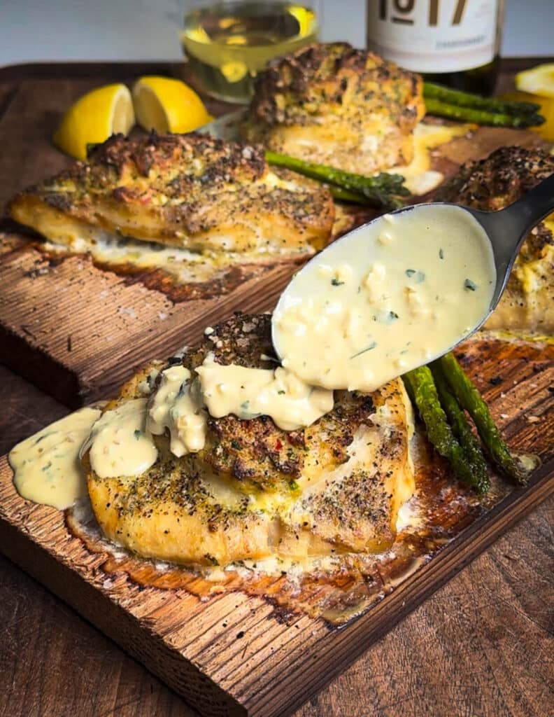 cream sauce being drizzled over crab stuffed grouper