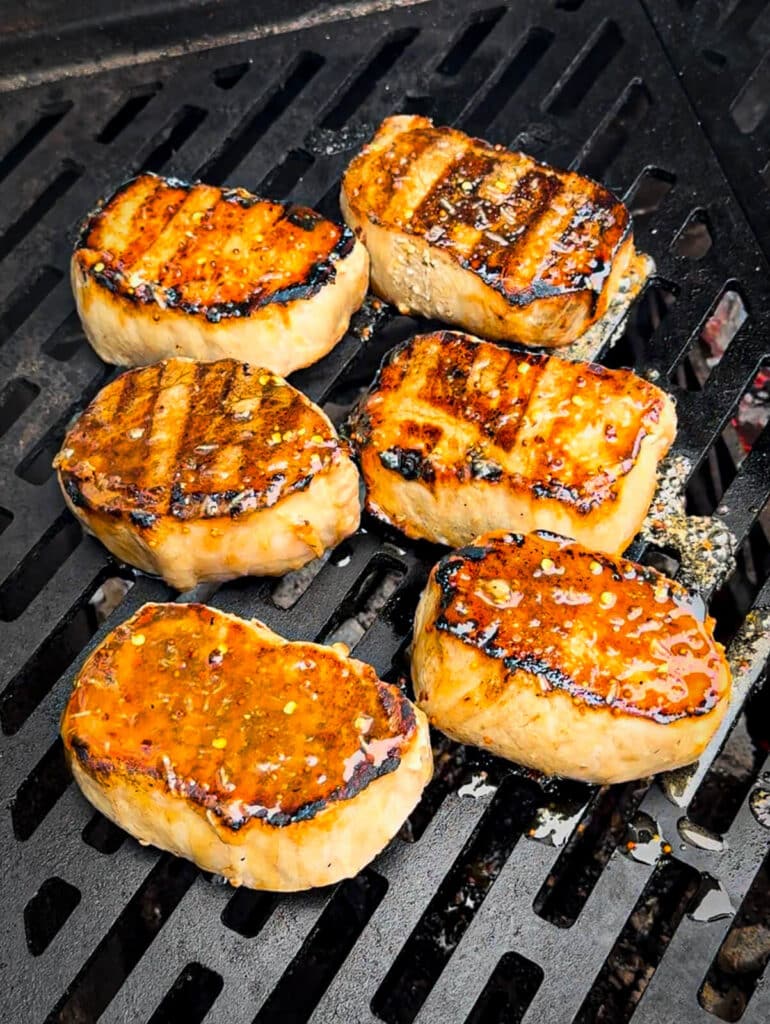 mustard glazed pork chops on a grill over indirect heat