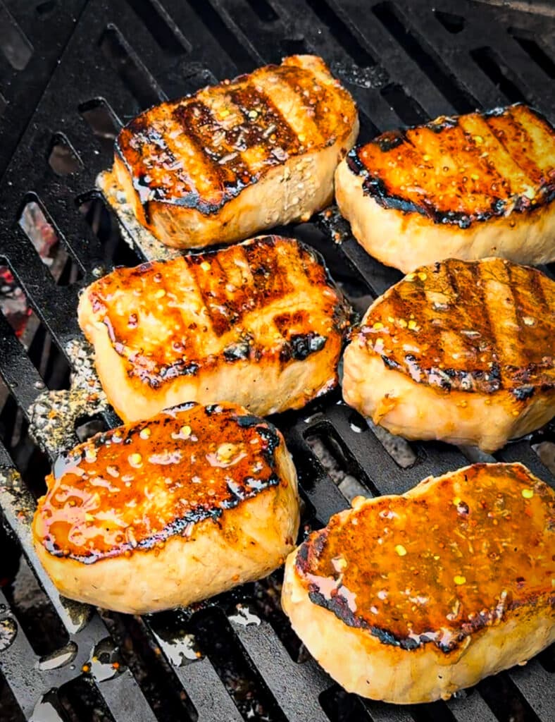 mustard glazed pork chops on a grill over indirect heat.