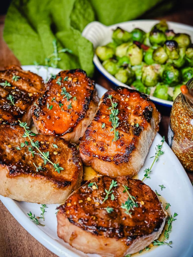 pork chops on a white platter, glazed with a mustard sauce