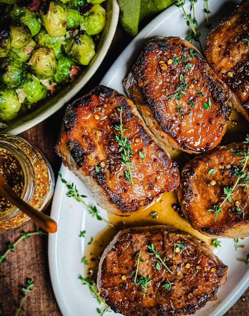 mustard glazed pork chops on a white platter with thyme