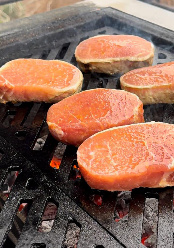 pork chops on a grill grate over hot coals