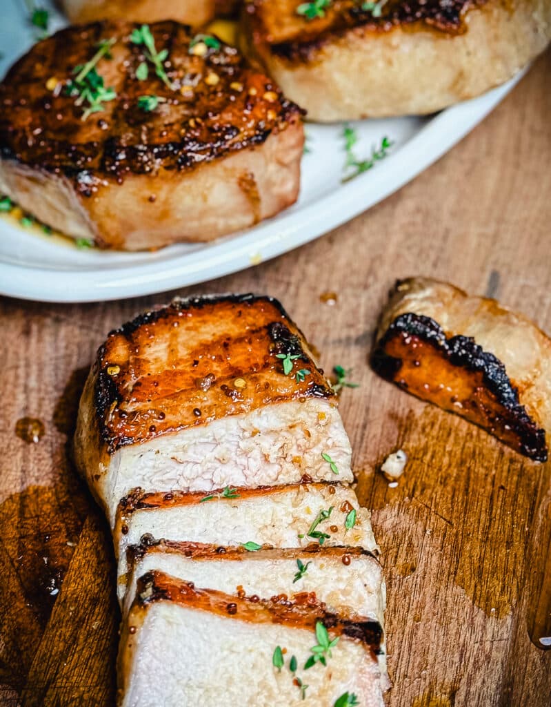 sliced mustard glazed pork chop on a cutting baord