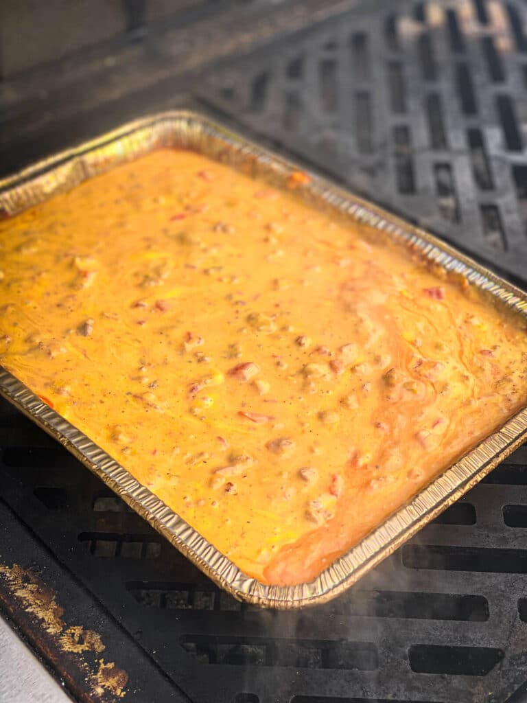 smoked queso dip on a grill, cheese melted